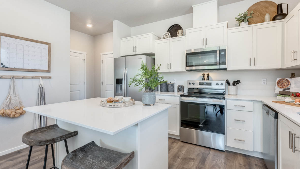 Kitchen with shaker cabinets, quartz counters, stainless steel appliances, pantry, and an island with a breakfast bar