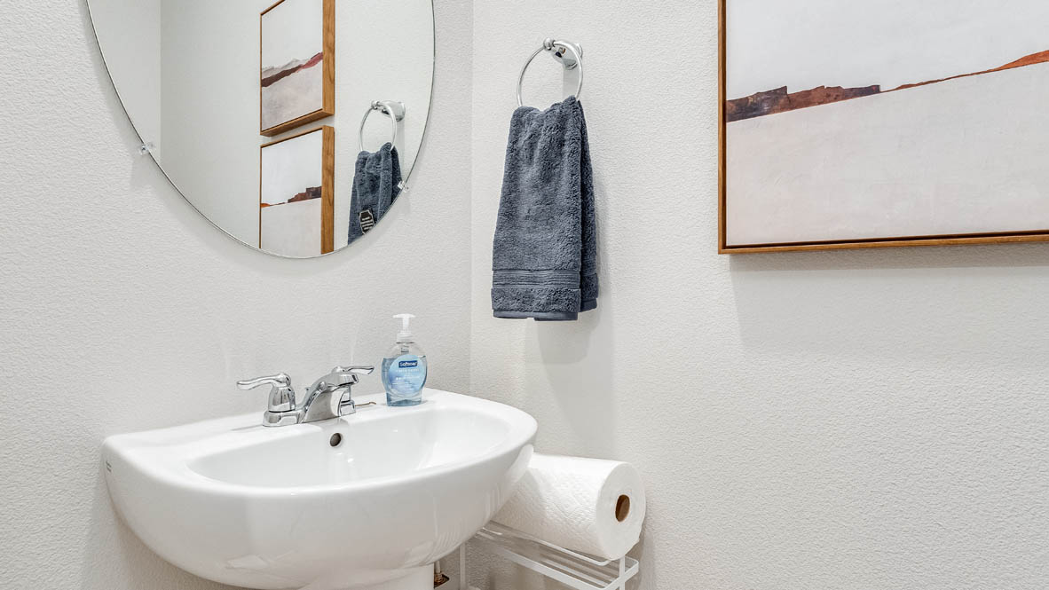 Butler Creek Crossing powder bathroom with single sink vanity, mirror, art, and blue hand towel