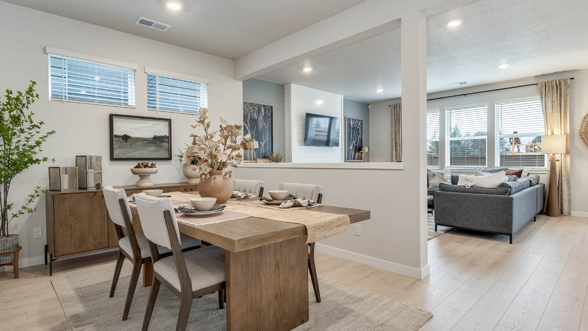 Butler Creek Crossing Dining room with four chairs set at the table placed over an area rug and connected to the great room with open barrier wall