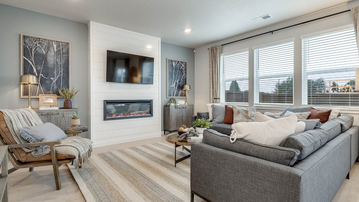 Butler Creek Crossing Great room with L shaped sectional couch facing the fireplace and TV over an area rug with a coffee table and chair in the corner