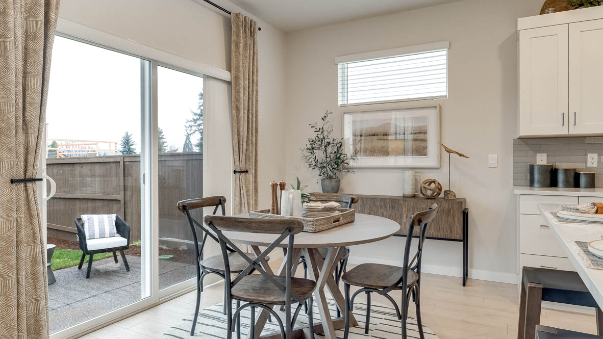 Butler Creek Crossing dining table with four chairs, high window, sliding glass door to the backyard, and the kitchen to the right