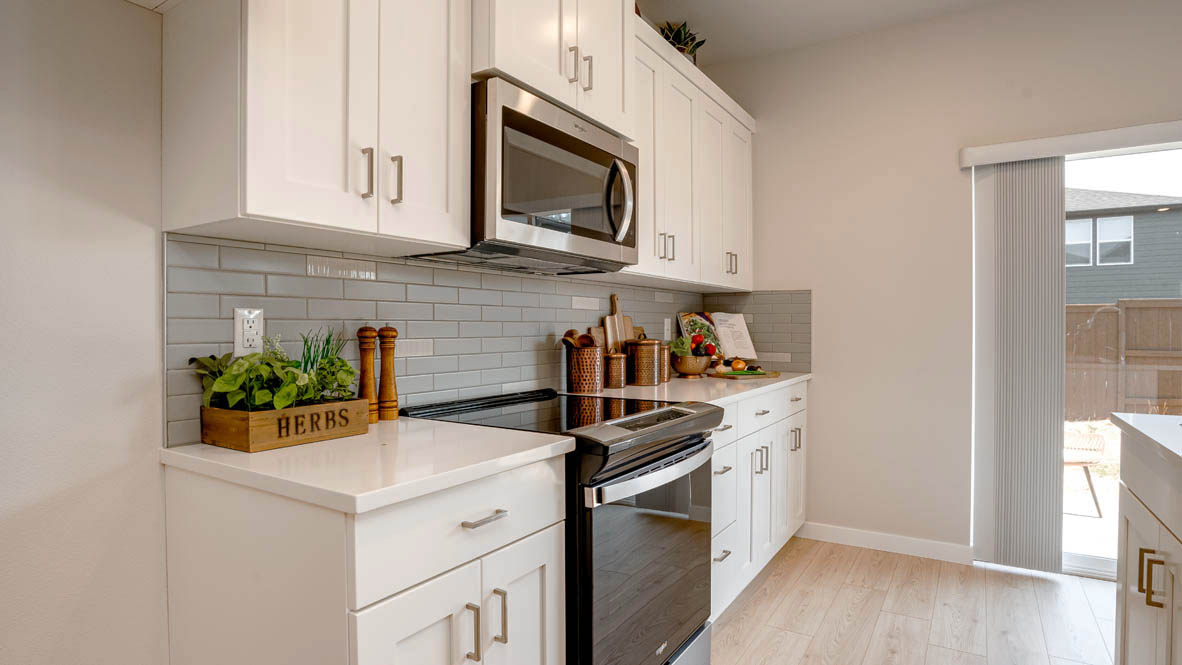 Butler Creek Crossing kitchen with shaker style cabinets and white solid surface countertops and full height backsplash
