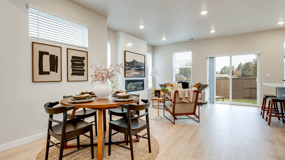 Butler Creek Crossing Dining room with four chairs set at the table placed over an area rug and connected to the great room, and the sliding glass door in the background