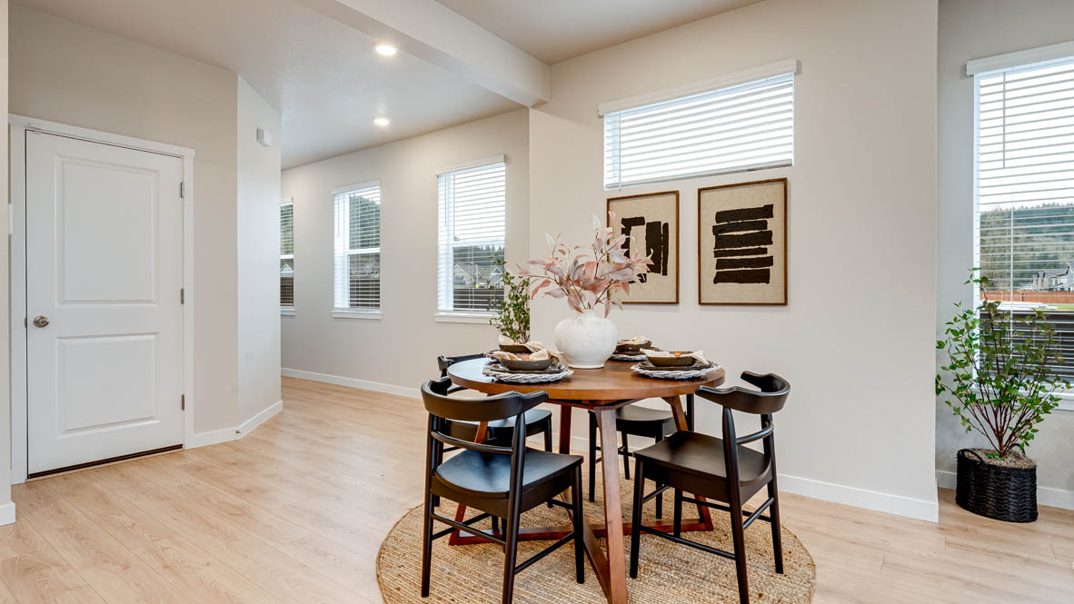 Butler Creek Crossing Dining room with four chairs set at the table placed over an area rug and connected to the great room, and the entry in the background