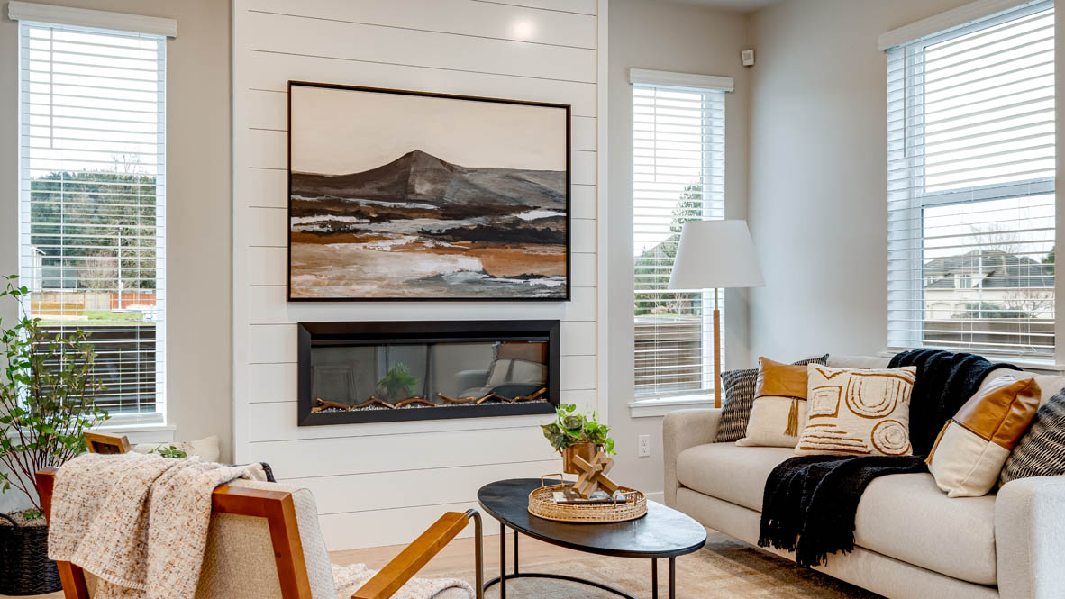 Butler Creek Crossing Great room with a couch facing the fireplace and painting over an area rug with a coffee table and chair in the corner