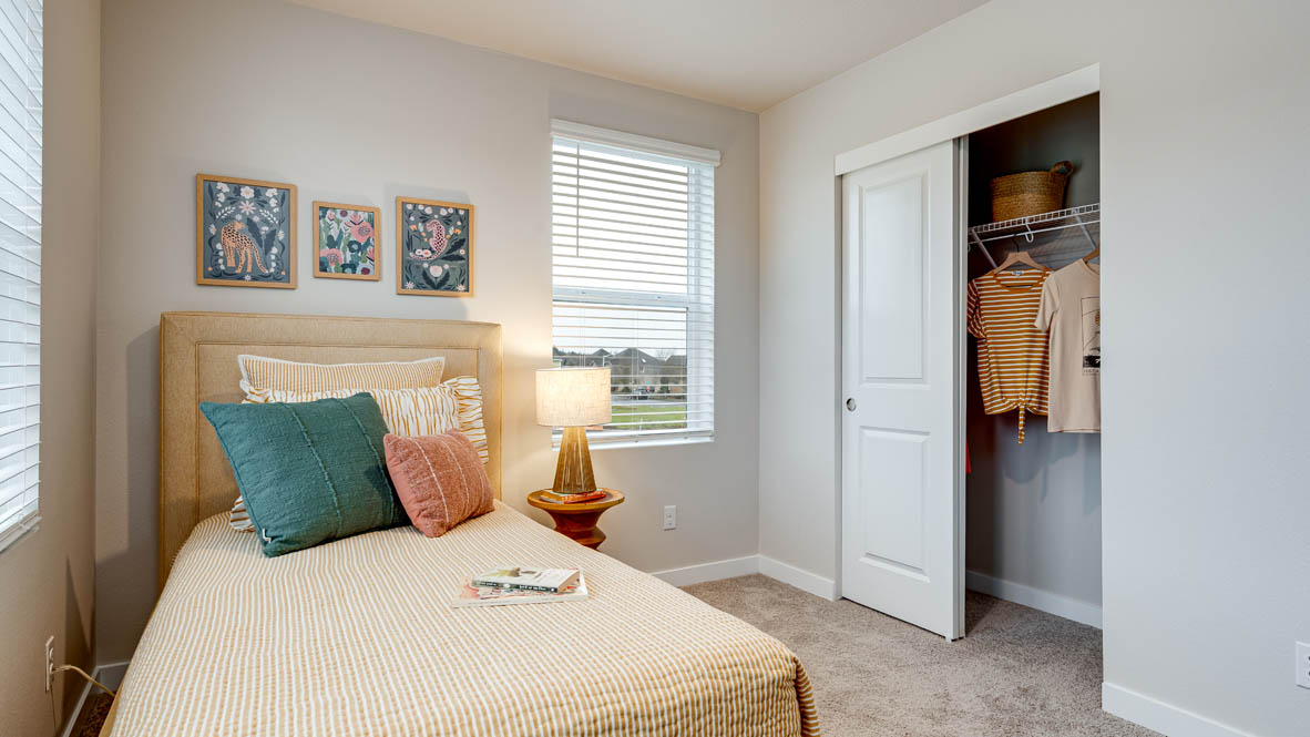 Butler Creek Crossing bedroom with side table and a lamp, bed, paintings, desk with a chair, and window with shades, and a closet