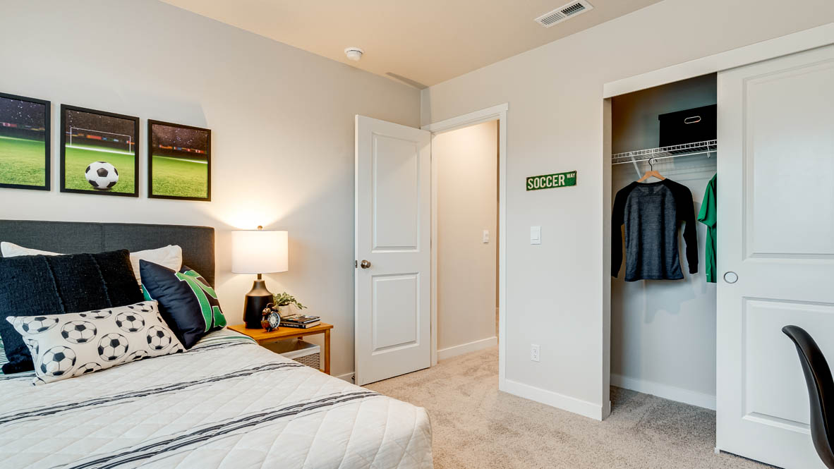 Butler Creek Crossing bedroom with side table and a lamp, bed, paintings, desk with a chair, and closet