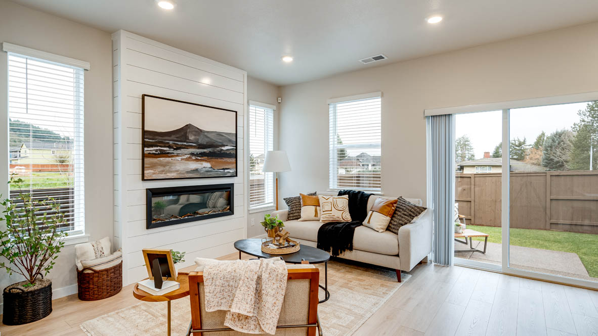 Butler Creek Crossing Great room with a couch facing the fireplace and painting over an area rug with a coffee table and chair in the corner