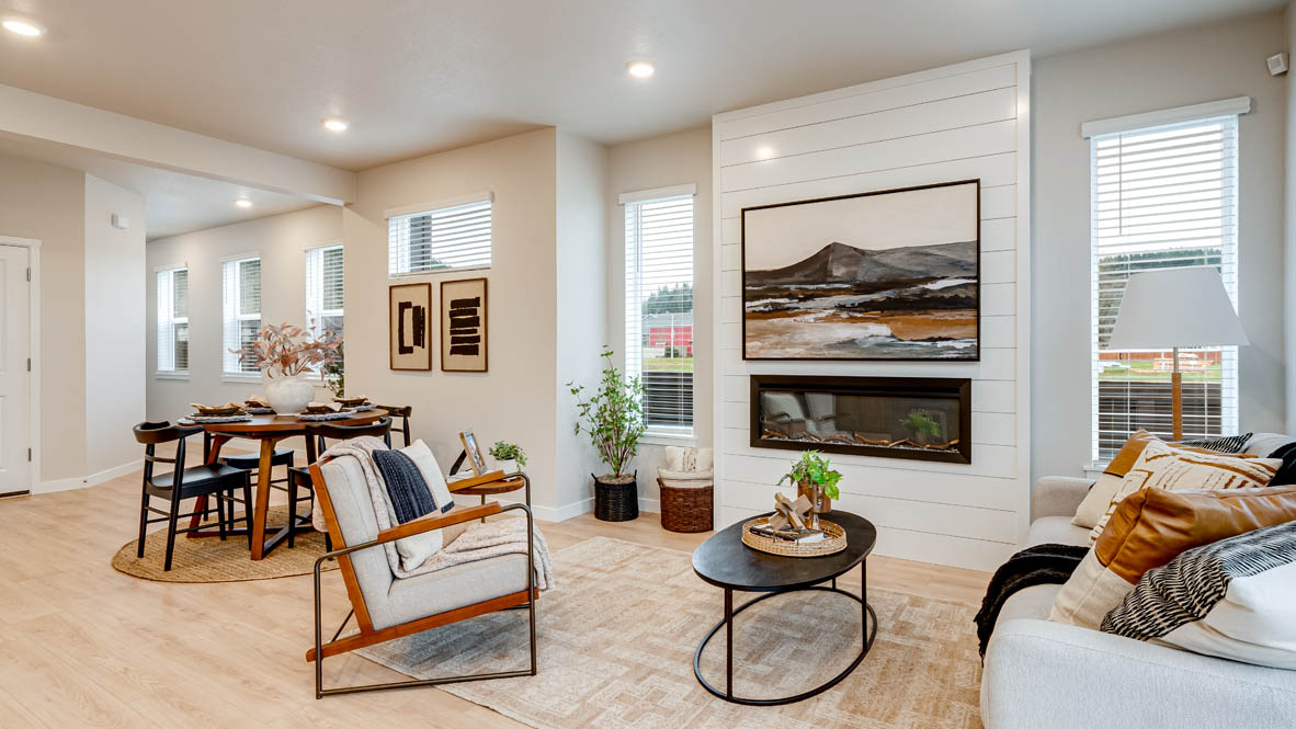 Butler Creek Crossing Great room with a couch facing the fireplace and painting over an area rug with a coffee table and chair in the corner