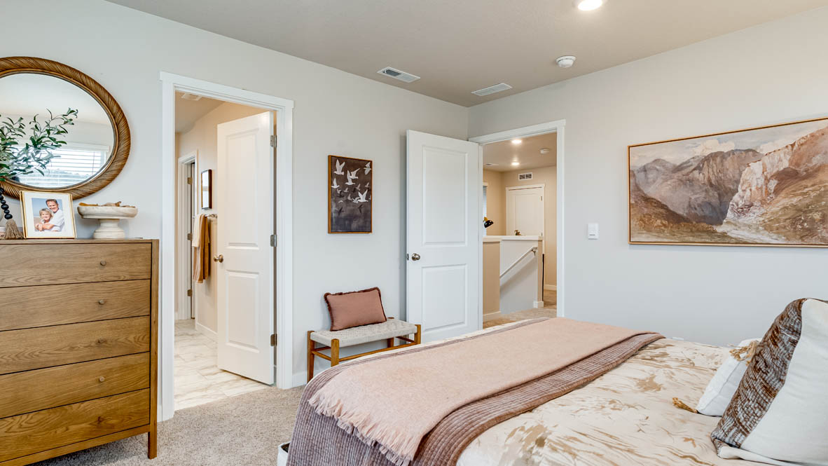 Butler Creek Crossing Primary bedroom with white carpet, painting, two lamps, a stool, dresser with a mirror, and the en suite bathroom in the background