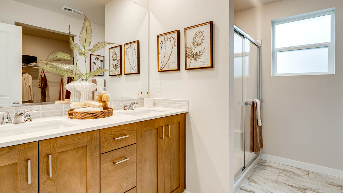 Butler Creek Crossing primary bathroom with flooring, shaker cabinets, vanity, quartz countertops, paintings, mirror