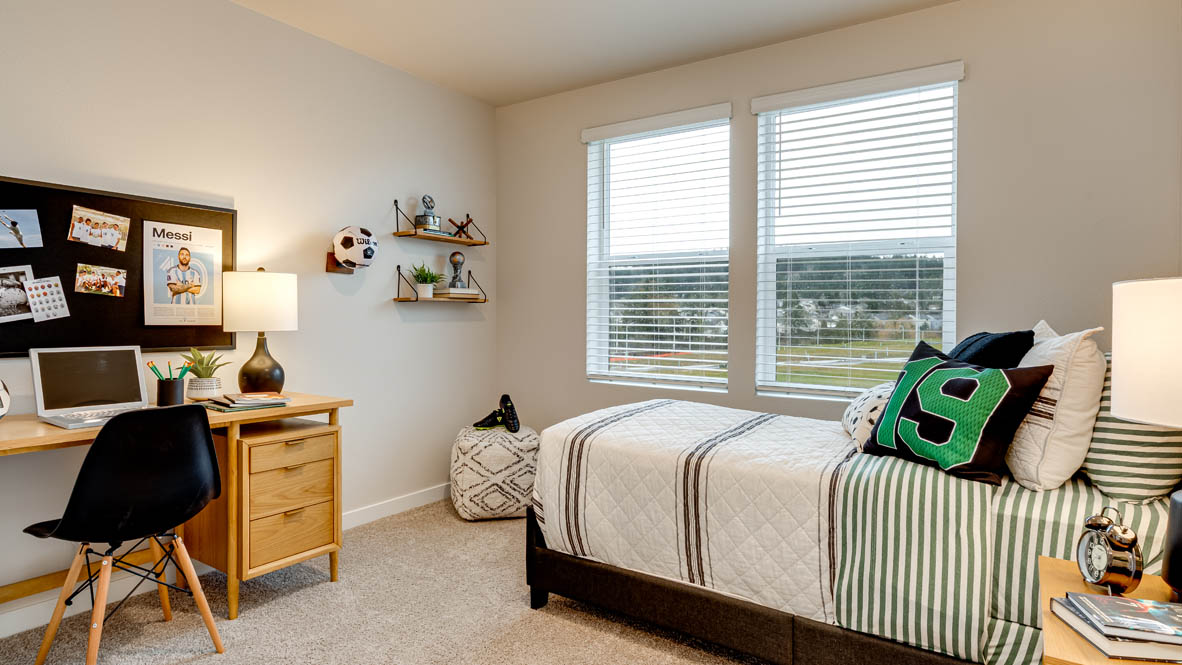 Butler Creek Crossing bedroom with side table and a lamp, bed, paintings, desk with a chair, and window with shades