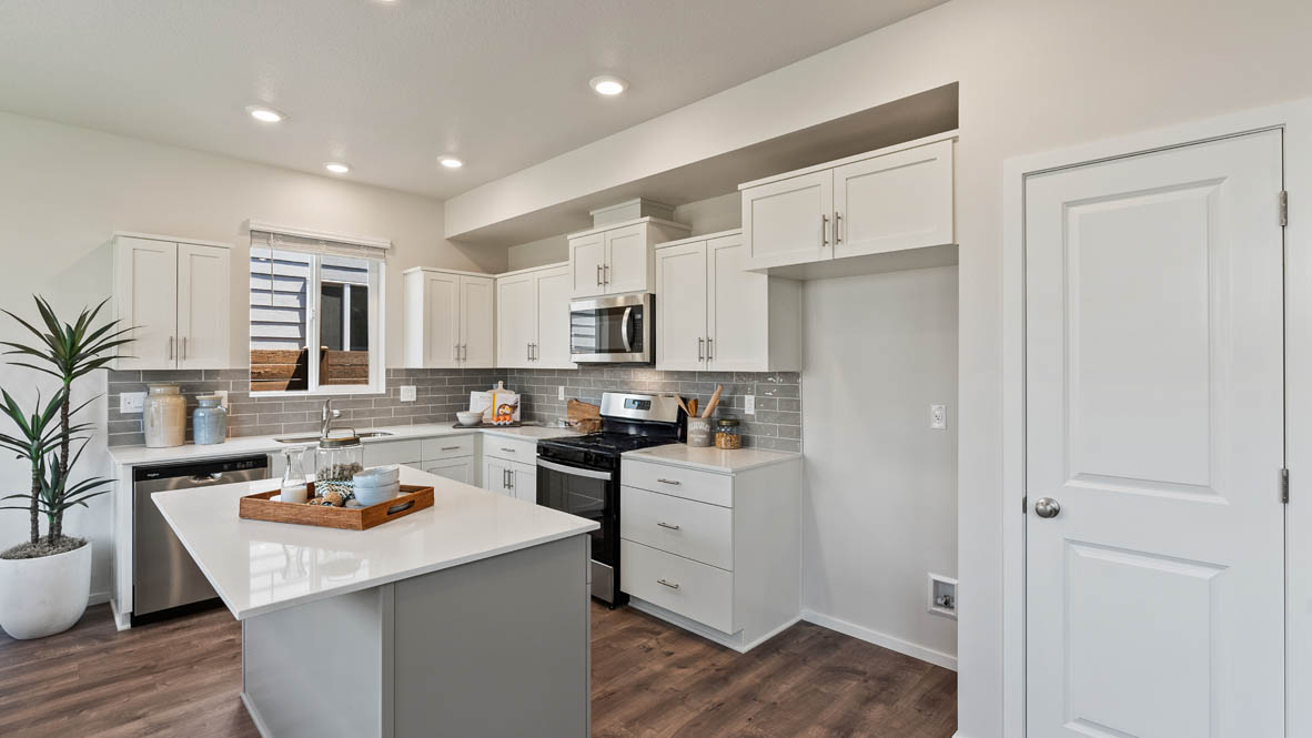 Butler Creek Crossing kitchen with window, stainless steel appliances, drawers, white stained cabinets, and pantry
