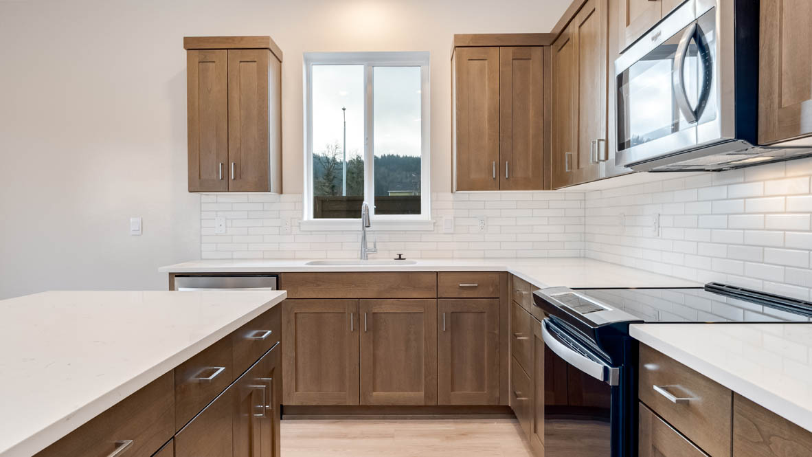 Butler Creek Crossing kitchen with window, stainless steel appliances, drawers, white stained cabinets, and pantry