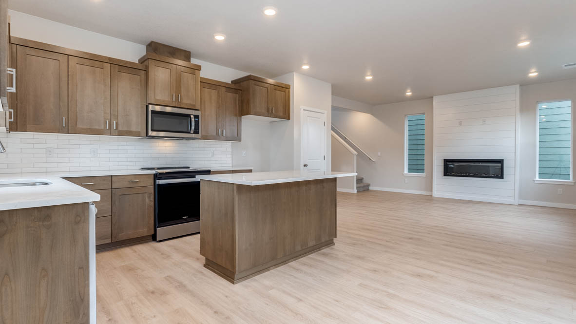 Butler Creek Crossing Dining Room with the kitchen in the background that includes stainless steel appliances, solid surface countertops, and laminate flooring