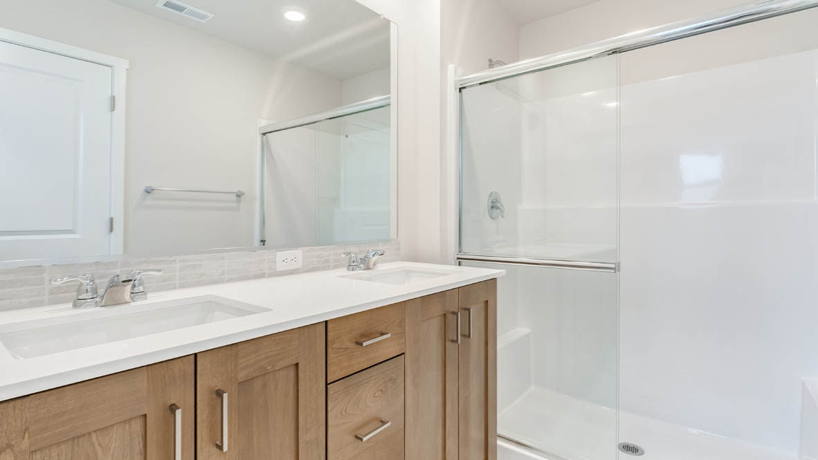 Butler Creek Crossing Primary Bathroom with countertops, cabinets, mirror, and sliding glass shower door