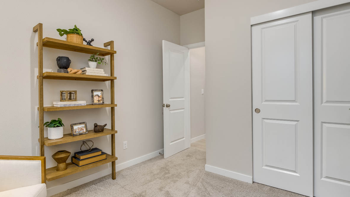 Butler Creek Crossing bedroom with side table and a lamp, bed, paintings, desk with a chair, and closet