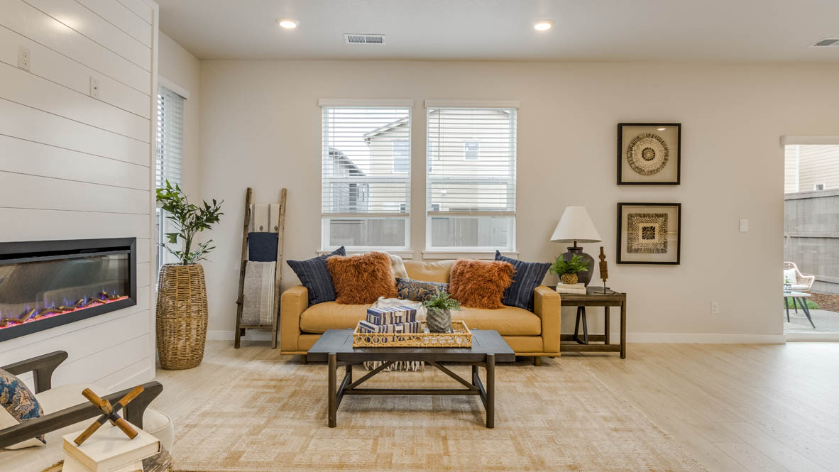 Butler Creek Crossing Great room with a couch facing the fireplace and painting over an area rug with a coffee table and chair in the corner