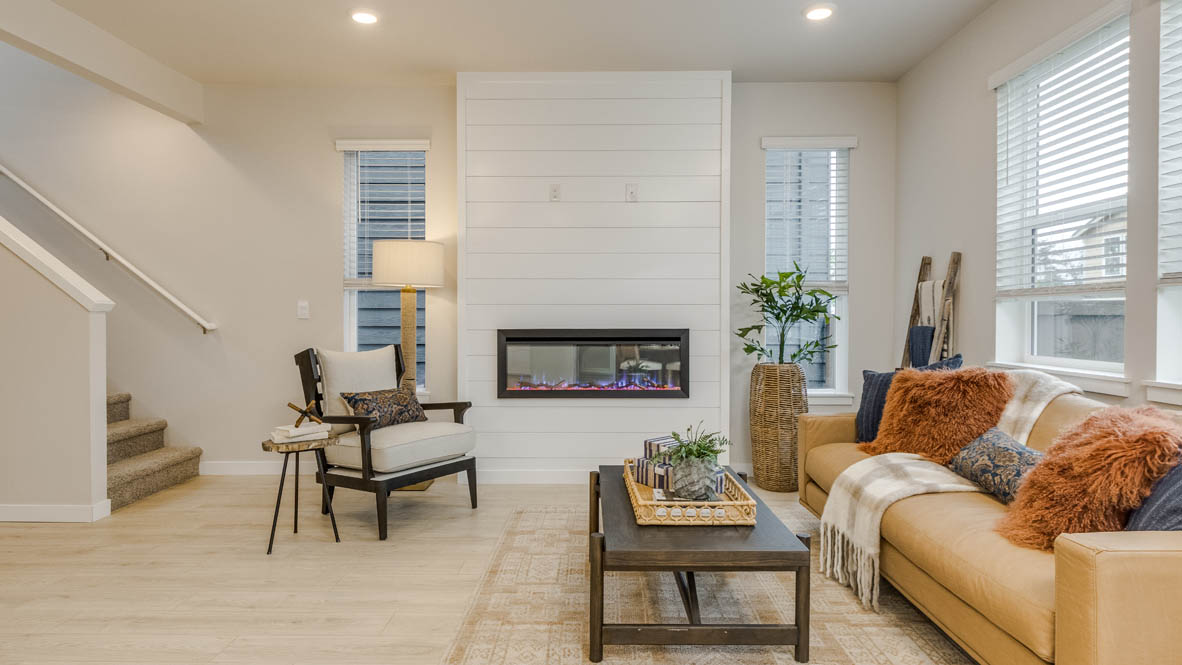Butler Creek Crossing Great room with a couch facing the fireplace and painting over an area rug with a coffee table and chair in the corner
