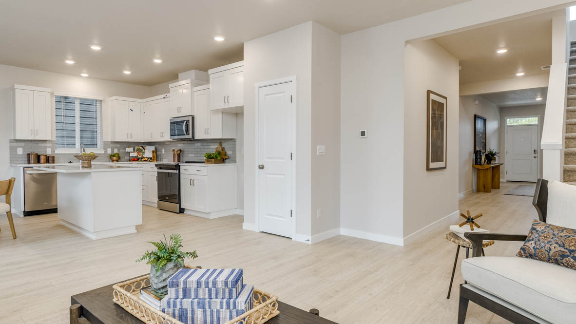 Butler Creek Crossing Kitchen with island that has white quartz countertops, two seats set up at the island, stainless steel appliances, a sliding glass door to the backyard, and stained shaker style cabinets