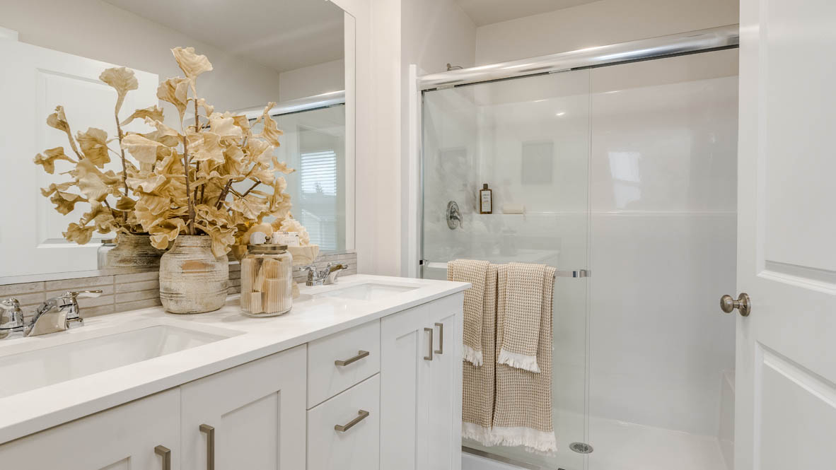 Butler Creek Crossing primary bathroom with flooring, shaker cabinets, vanity, quartz countertops, paintings, mirror
