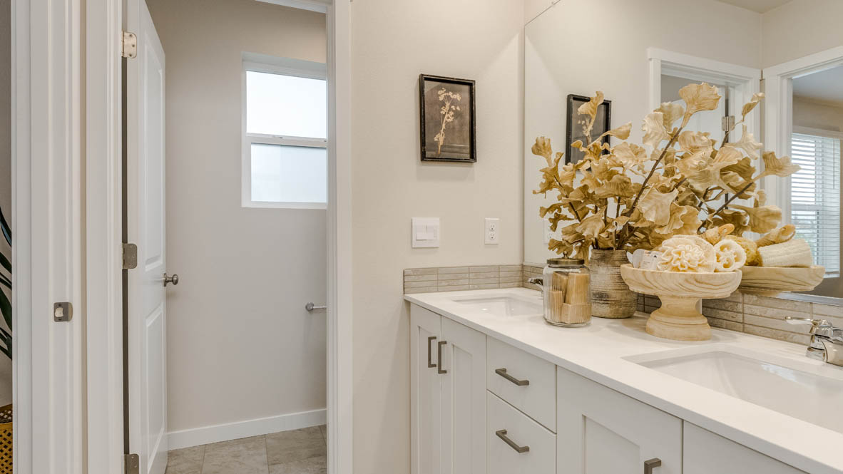 Butler Creek Crossing primary bathroom with flooring, shaker cabinets, vanity, quartz countertops, paintings, mirror