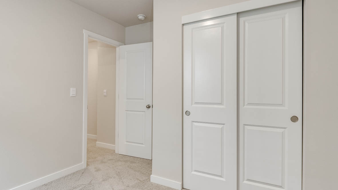 Butler Creek Crossing bedroom with side table and a lamp, bed, paintings, desk with a chair, and window with shades, and a closet