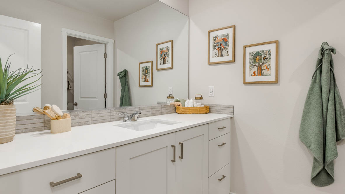 Butler Creek Crossing Secondary Bathroom with single sink vanity, orange accent towels, paintings, quartz countertops, and a toilet