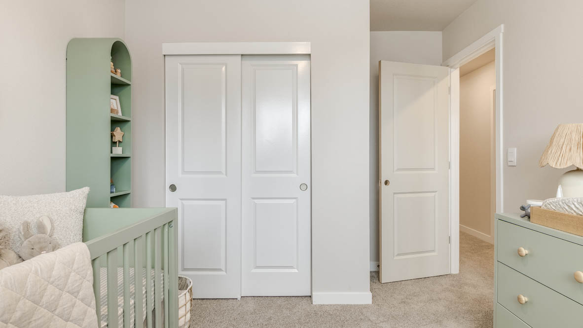 Butler Creek Crossing bedroom with side table and a lamp, bed, paintings, desk with a chair, and window with shades, and a closet