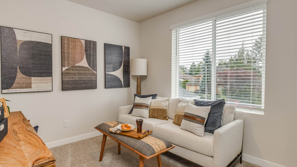 Butler Creek Crossing bedroom with side table and a lamp, bed, paintings, desk with a chair, and window with shades