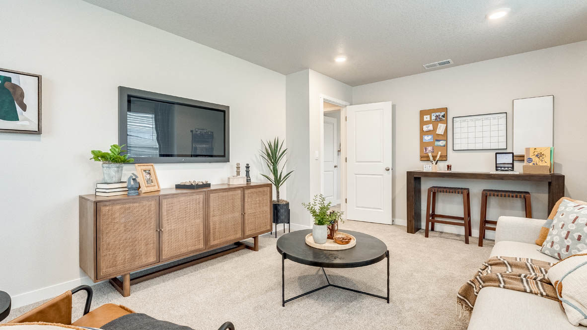 Butler Creek Crossing bonus bedroom with two paintings, coffee table, white carpet, couch with pillows, two chairs, a lamp, console table, entertainment center