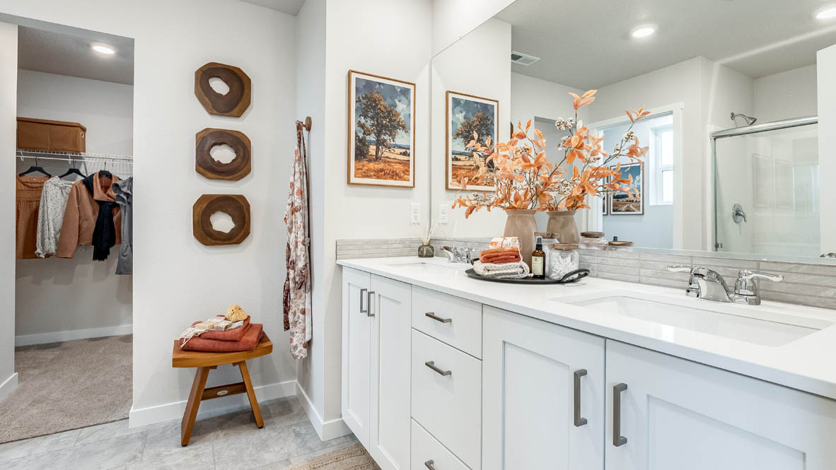 Butler Creek Crossing primary bathroom with flooring, shaker cabinets, double vanity, quartz countertops, walk-in closet, paintings, mirror