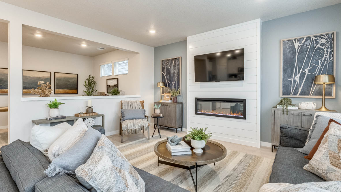 Butler Creek Crossing Great room with L shaped sectional couch facing the fireplace and TV over an area rug with a coffee table and chair in the corner