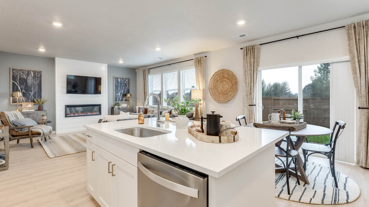 Butler Creek Crossing Kitchen with island that has white quartz countertops, two seats set up at the island, stainless steel appliances, a sliding glass door to the backyard, and white shaker style cabinets