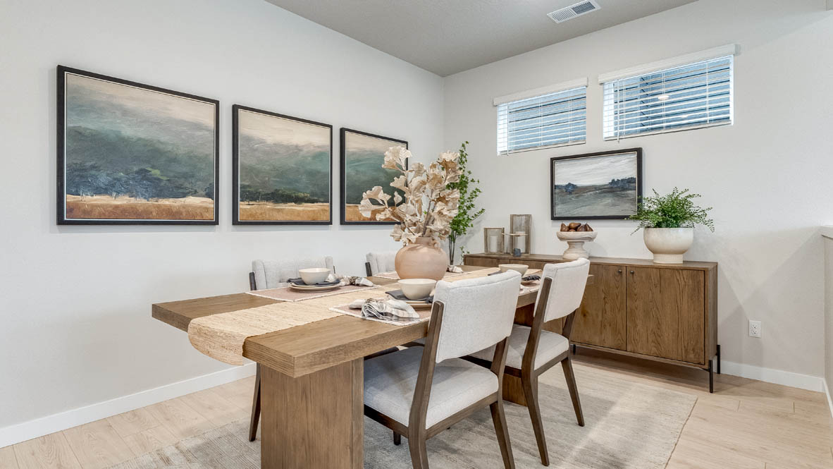 Butler Creek Crossing Dining room with four chairs set at the table and an area rug underneath. To the left there is a mirror over a console against the wall