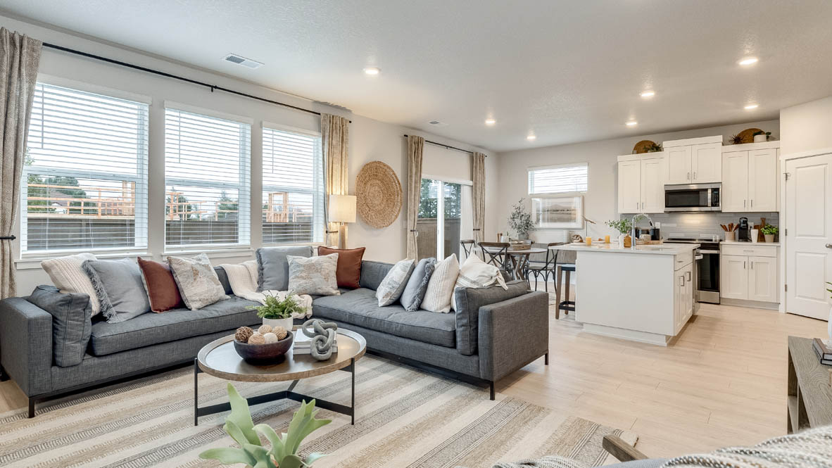 Butler Creek Crossing Great room with L shaped sectional couch facing the fireplace and TV over an area rug with a coffee table and chair in the corner