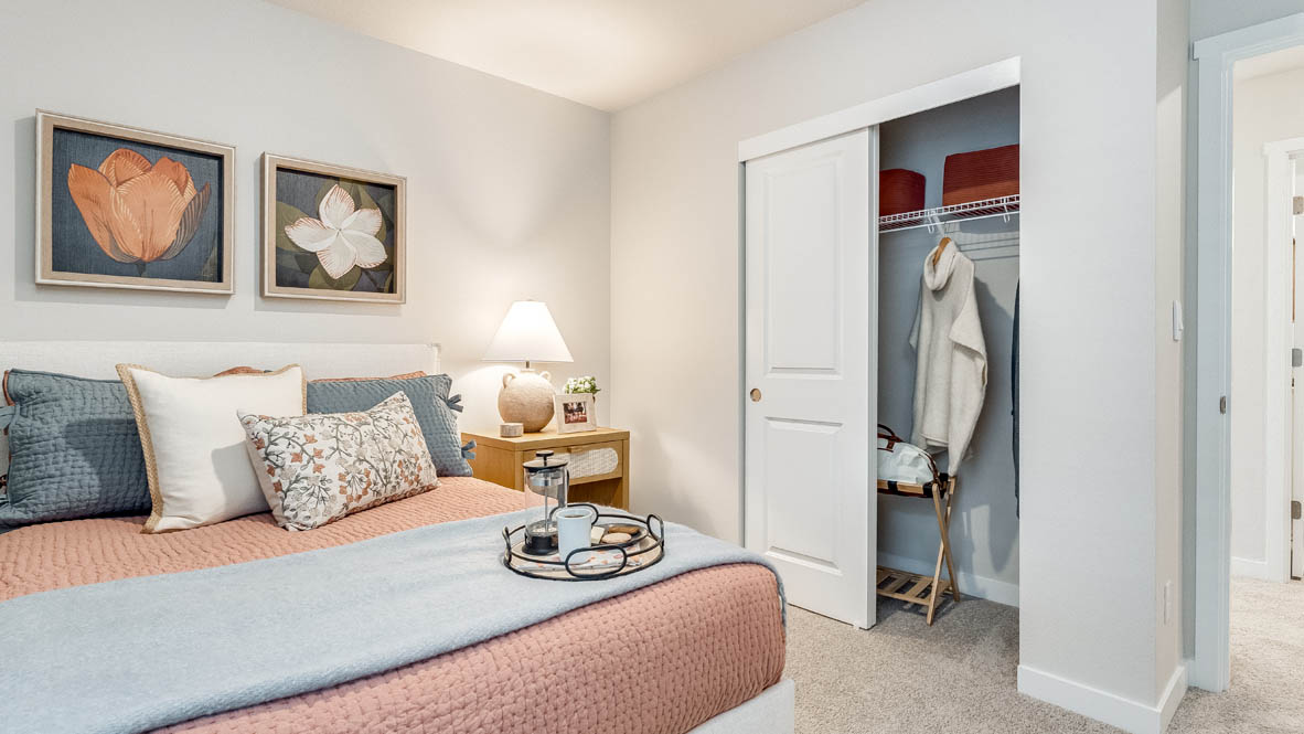 Butler Creek Crossing bedroom with side table and a lamp, bed, paintings, desk with a chair, and window with shades