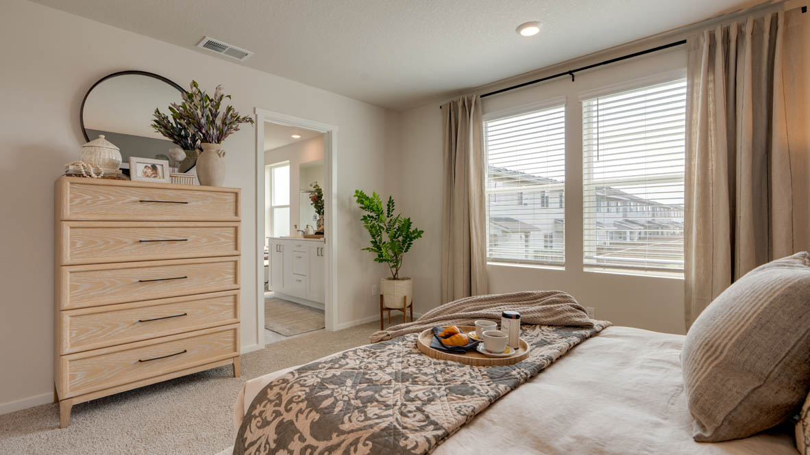 Bailey Meadows primary bedroom with accent wall and carpeting with light colored wooden furniture