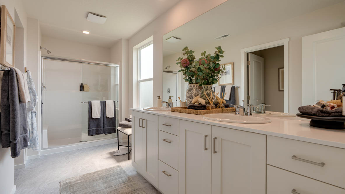 Bailey Meadows primary bathroom with white shaker style cabinets and a double sink vanity with a walk in closet and walk in shower