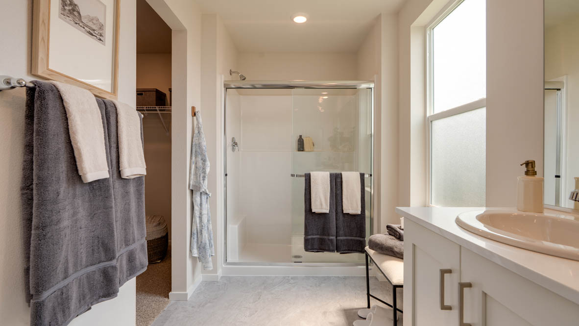 Bailey Meadows primary bathroom with white shaker style cabinets and a double sink vanity with a walk in closet and walk in shower