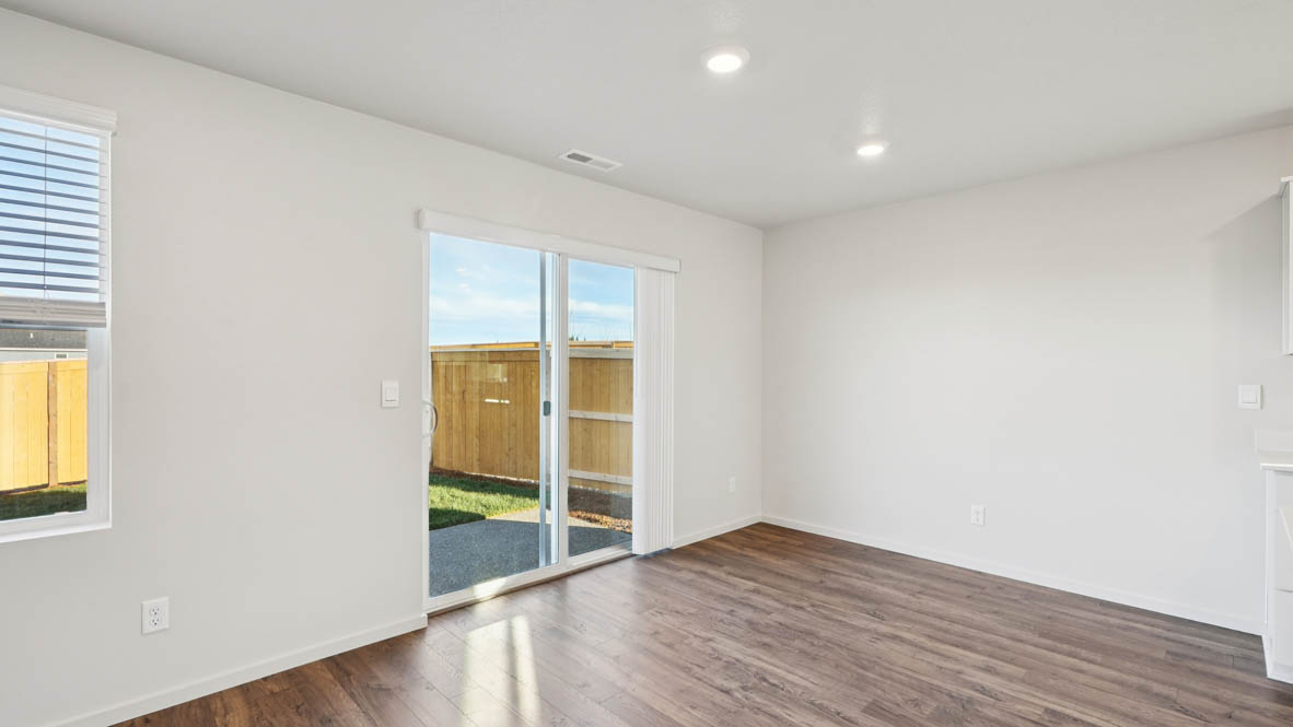East Park Village great room with sliding glass doors laminate flooring and white walls and two windows