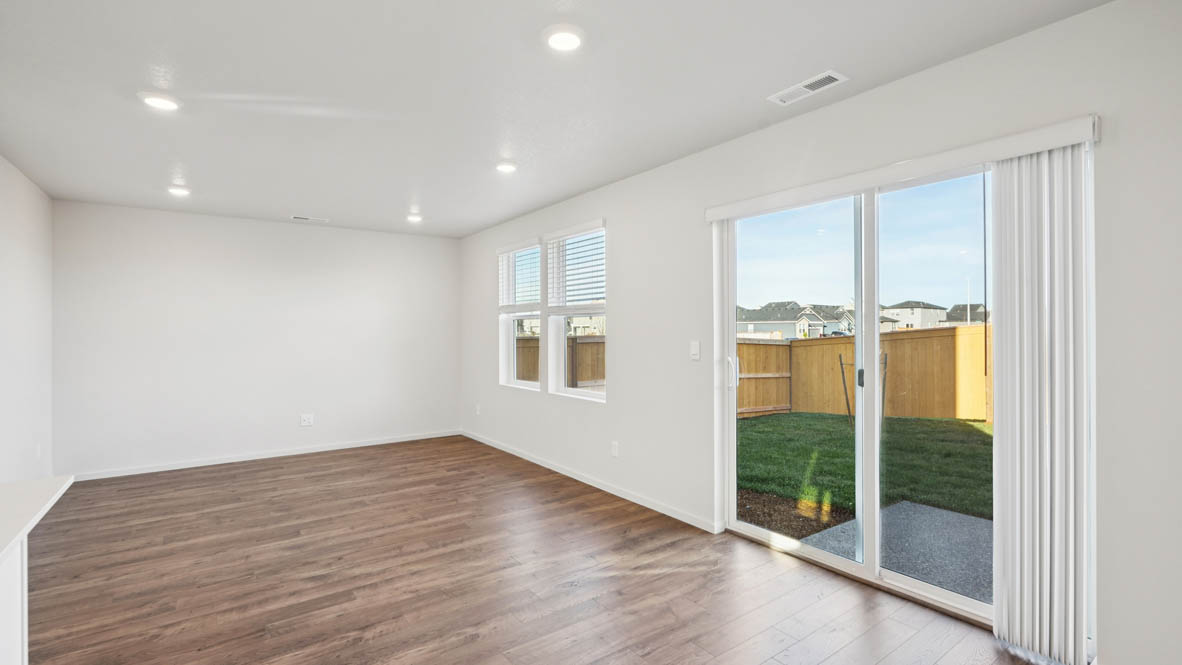 East Park Village great room with sliding glass doors laminate flooring and white walls and two windows