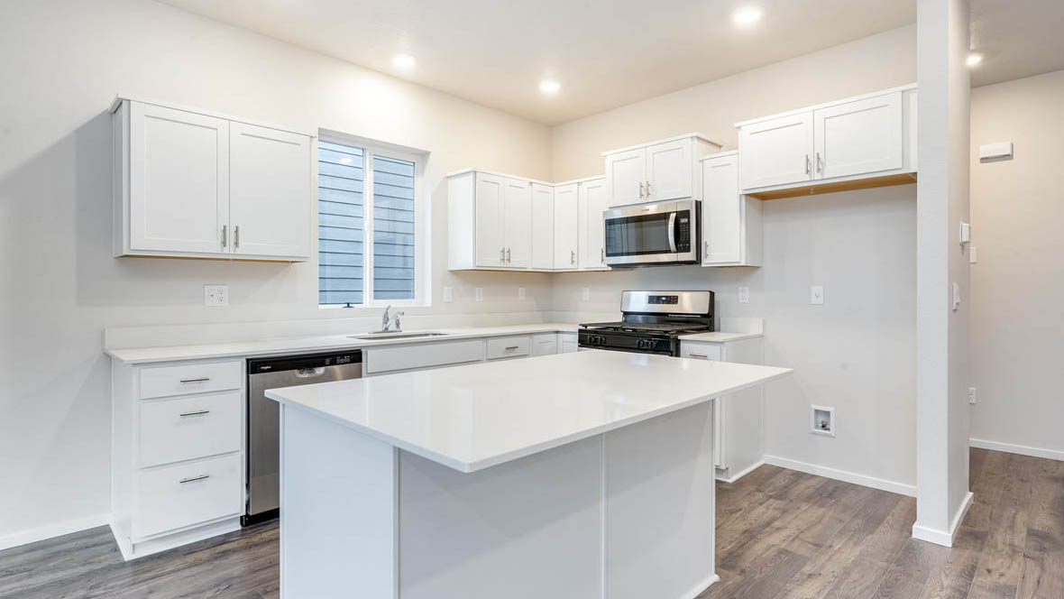 East Park Village kitchen with white cabinets, solid surface countertops, window, and stainless steel appliances