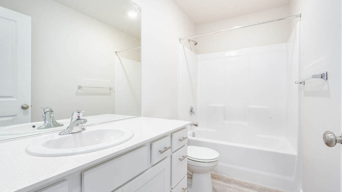 East Park Village bathroom with vanity, mirror, toilet, tub shower, and white cabinets