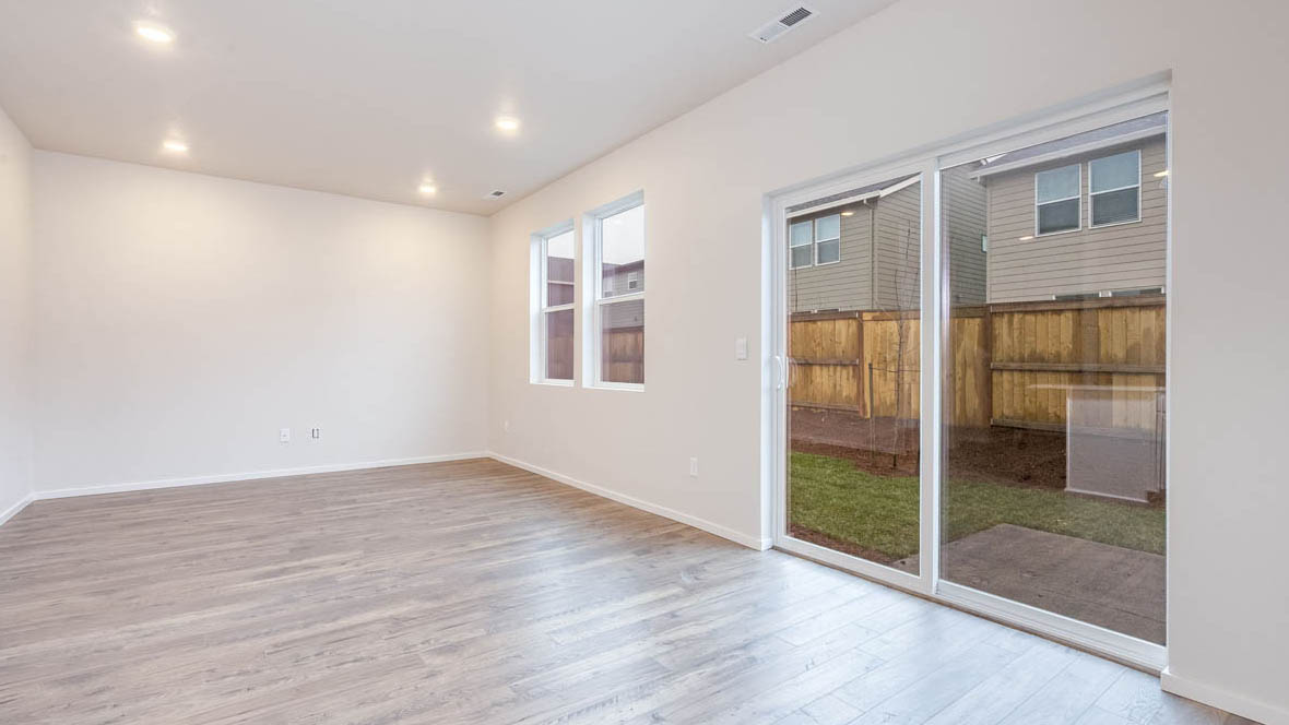 East Park Village great room with sliding glass doors laminate flooring and white walls and two windows