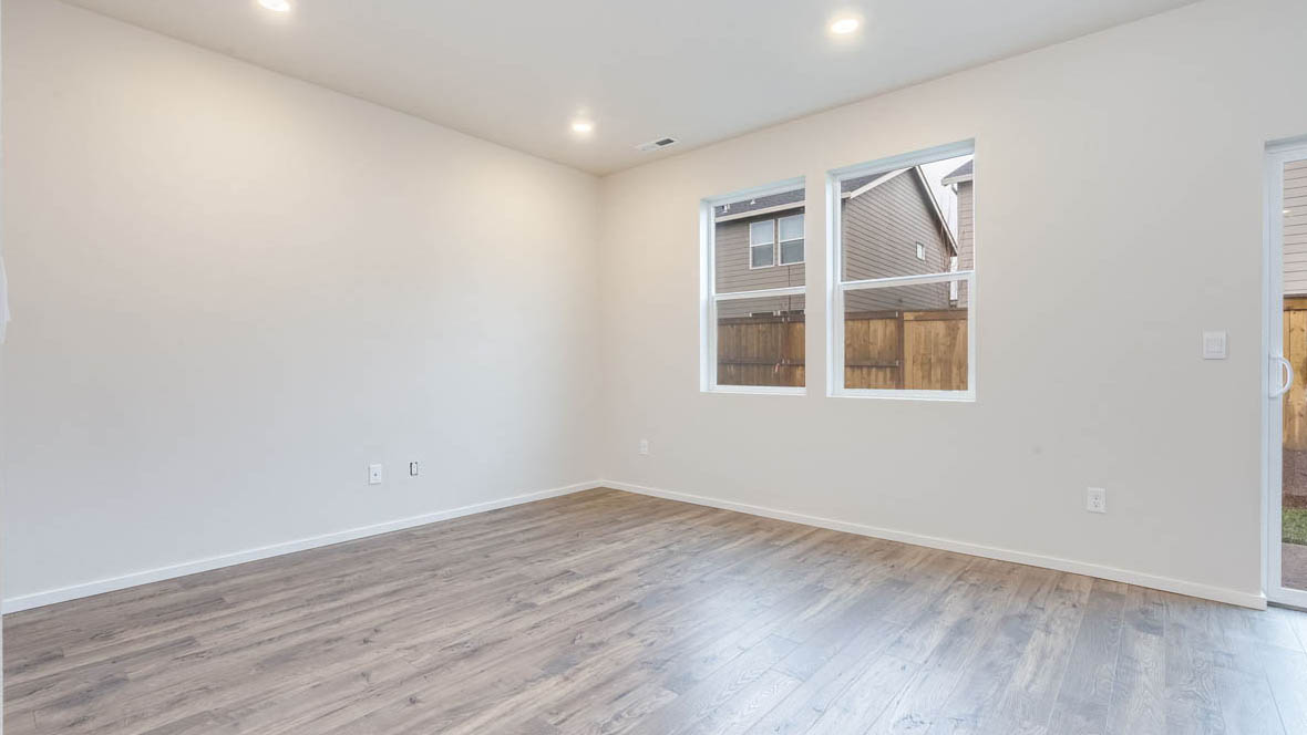 East Park Village great room with sliding glass doors laminate flooring and white walls and two windows