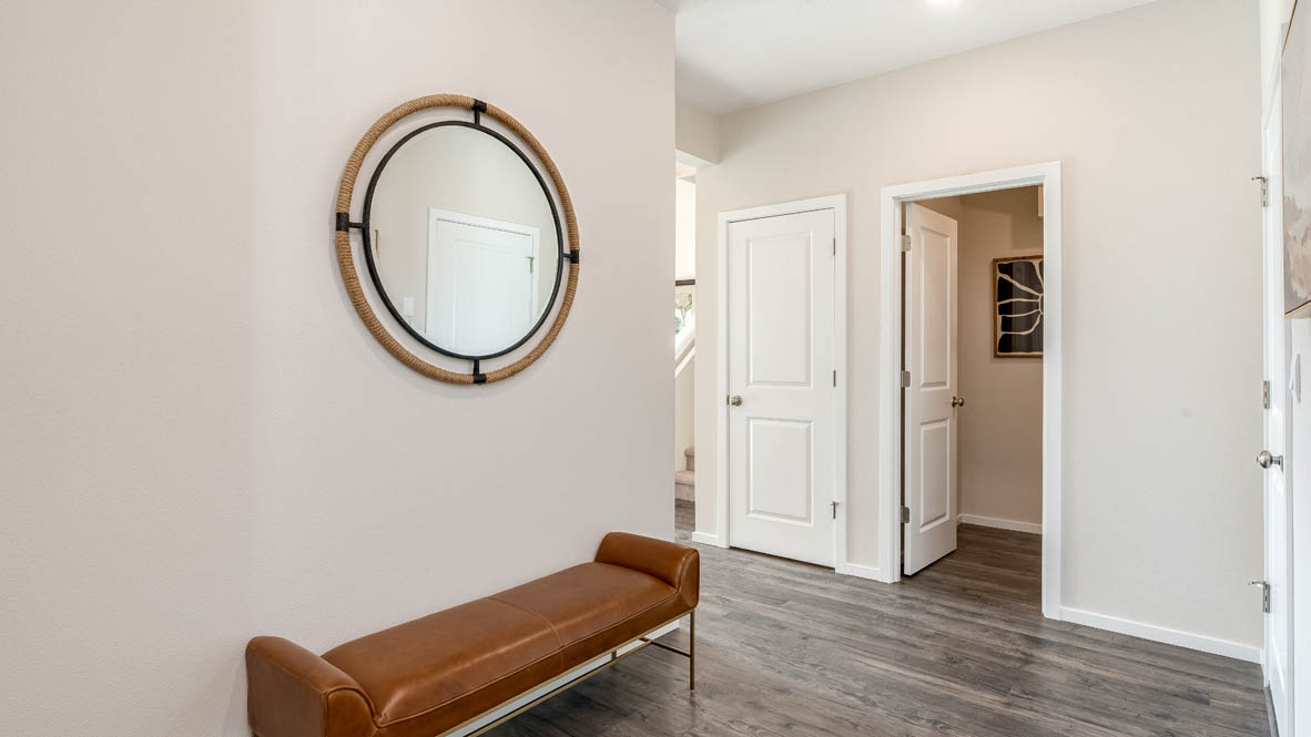 East Park Village Entry with brown rest chair and mirror, laminate flooring, and view of powder room