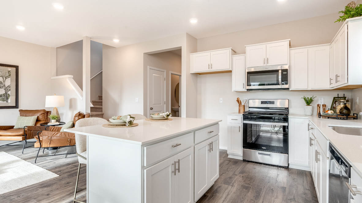 East Park Village Kitchen with island and a breakfast bar, two chairs, white cabinets, stainless steel appliances, quartz countertops, a window, decorations, and laminate flooring