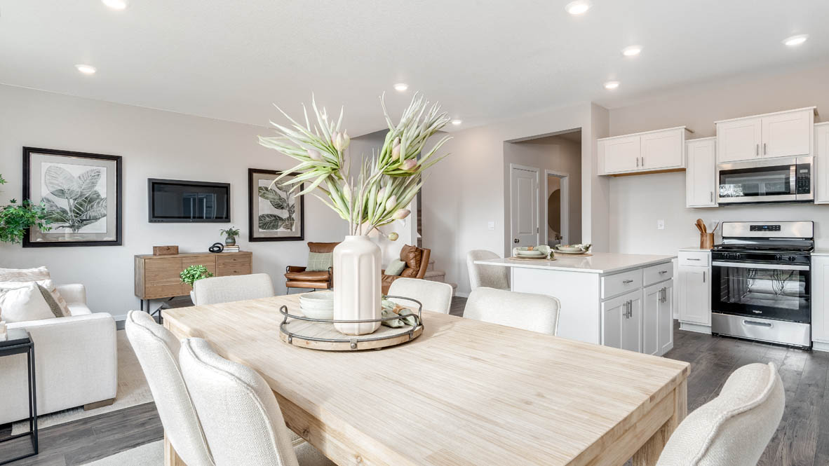 East Park Village Dining Room with four chairs, a table, a plant, sliding glass door, hanging decorations, a side table, and view of kitchen and great room
