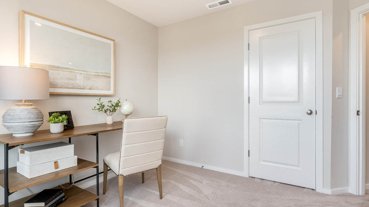 East Park Village Bedroom office with a closet, a painting, desk, chair, and lamp with a plant